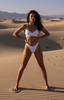 Woman in a white bikini standing in a desert landscape