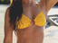 Person wearing a yellow bikini top with gold hardware  
